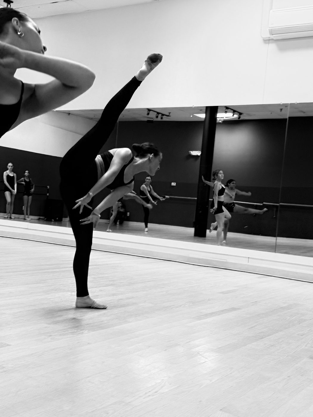 A dancer holding a tilt in front of the mirror